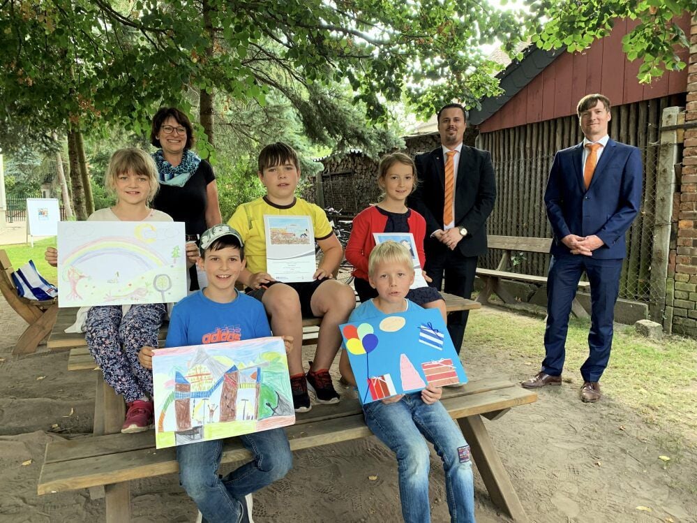 Volksbank-Kundenberater Stefan Lutzmann (v.r.) und Marktbereichsleiter der Volksbank, Rico Lange überreichen den Kindern ihre Preise. Schulleiterin Betty Riedel freut sich mit ihren Schülern.