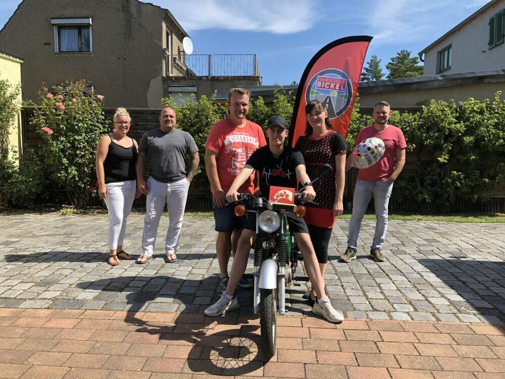 Mandy und Nico Brandtner vom Verein Herzensangelegenheit (li. ) und Stefan Bickel von der Fahrschule Bickel (re. ) schenken Robin Erlebach (Mitte) einen Gutschein für seinen Moped-Führerschein. Mama Romy Erlebach und ihr Lebensgefährte Jan Godziszewski haben bereits das Moped organisiert.