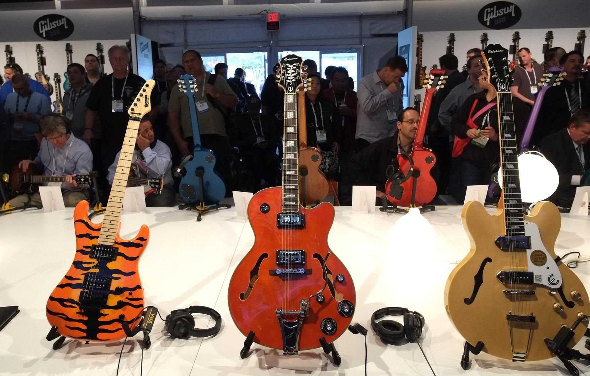 Besucher nehmen Gibson-Gitarren auf einer Messe unter die Luipe