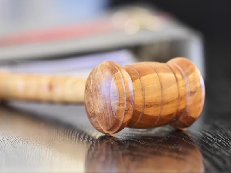Ein Richterhammer aus Holz auf einer Richterbank. Foto: Uli Deck/Archiv