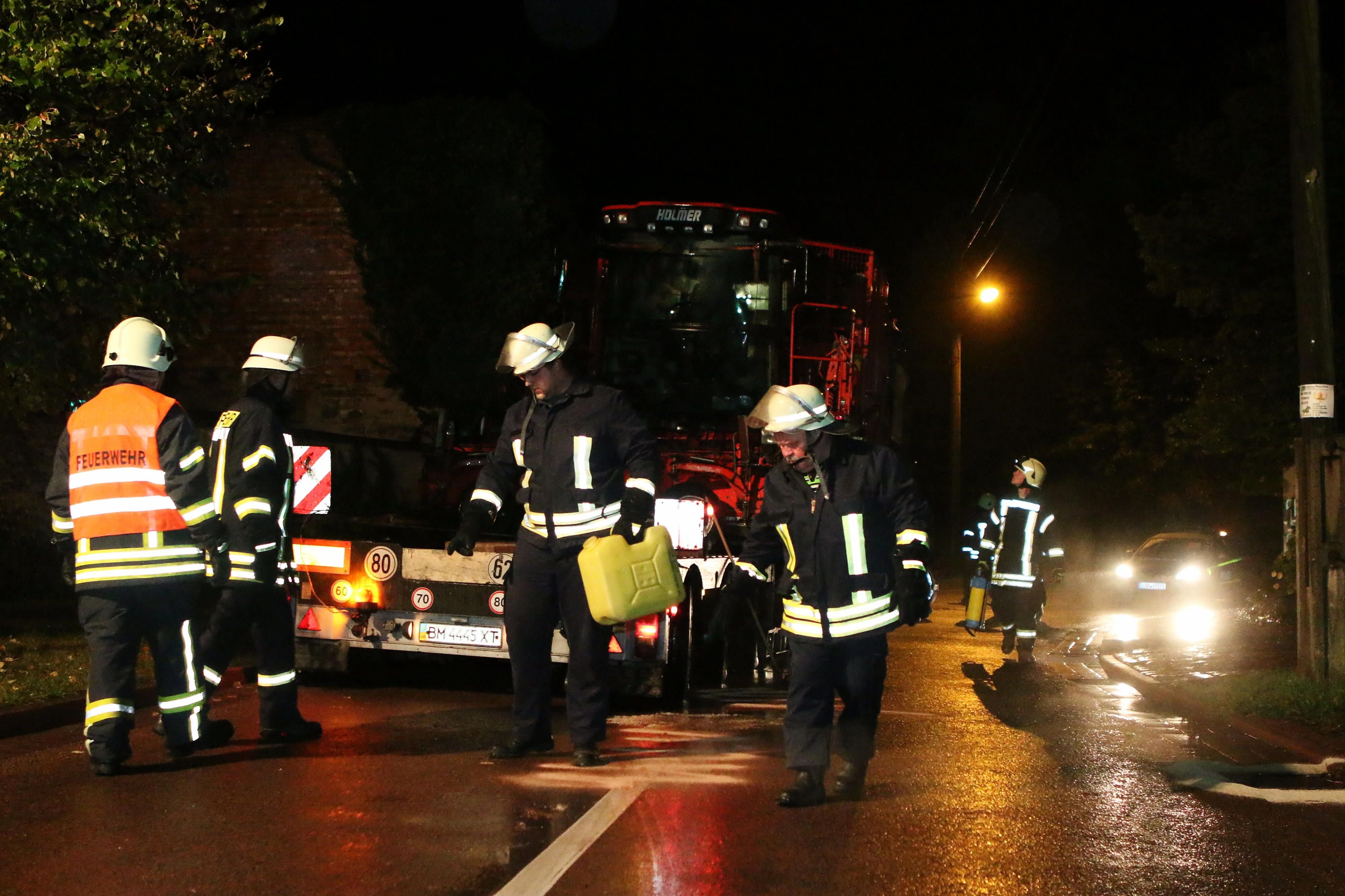 Feuerwehrleute beseitigen die Ölspur auf der Fahrbahn.