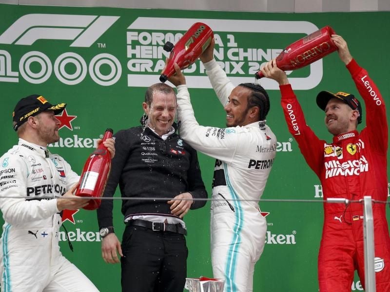 Sebastian Vettel (r) spendiert für Sieger Lewis Hamilton eine Champagner-Dusche. Foto: Andy Wong/AP