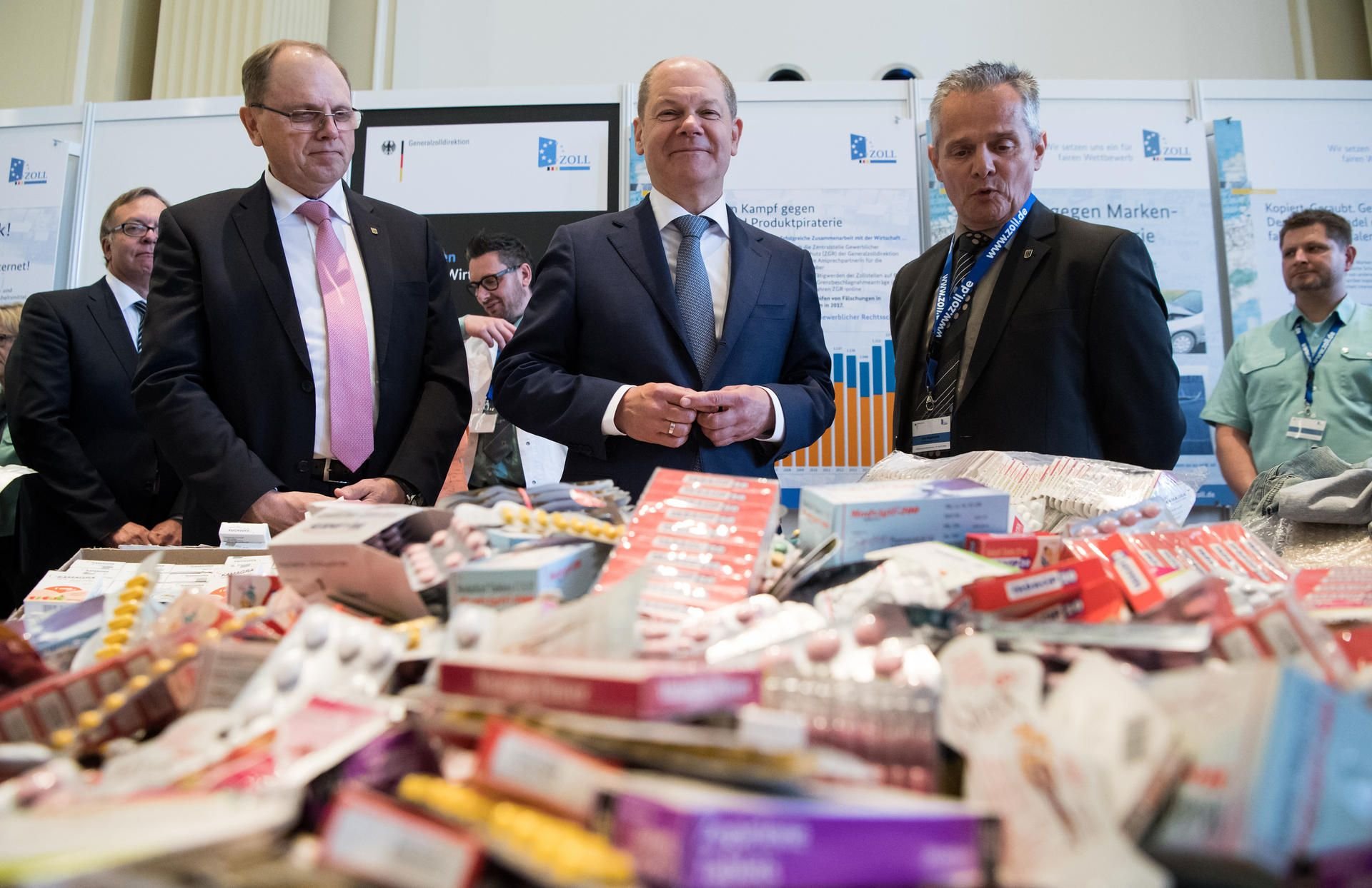 Bundesfinanzminister Olaf Scholz (Mitte, SPD) schaut sich mit Hans Josef Haas (links), Vizepräsident der Generalzolldirektion, bei der Vorstellung der Jahresbilanz des Zolls für 2017 im Bundesfinanzministerium einige Ausstellungstücke von geschmuggelten Medikamenten an.
