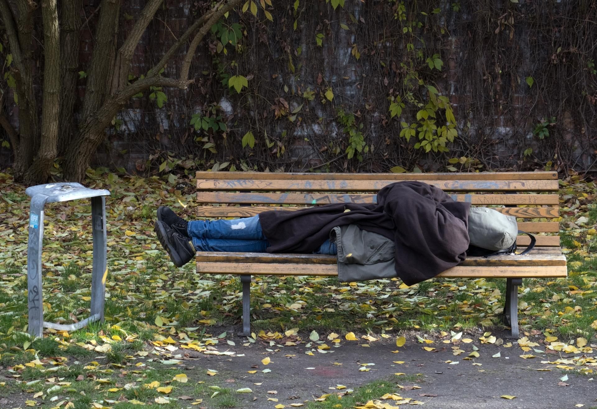 Ein Obdachloser schläft in Berlin auf einer Parkbank.