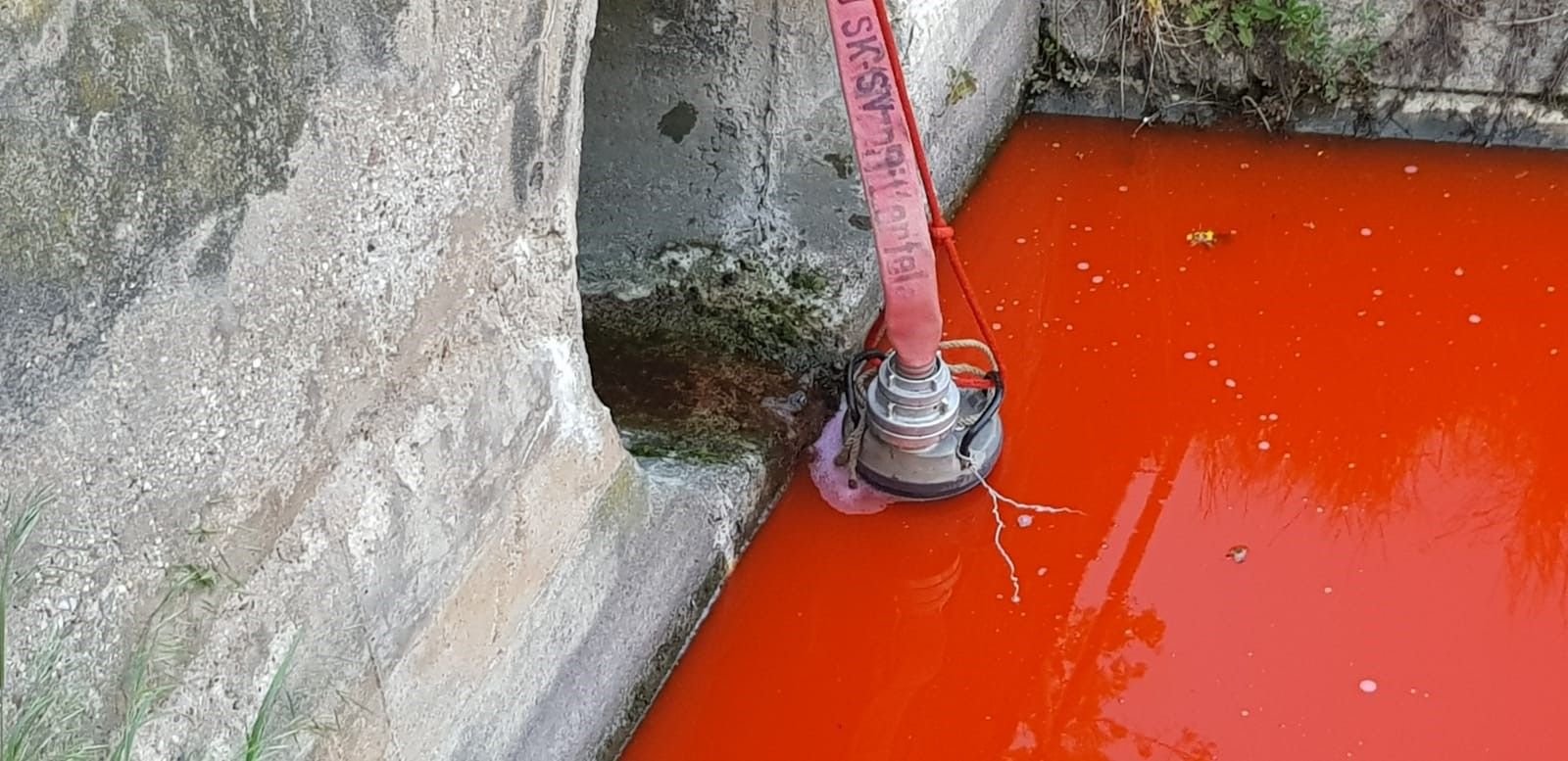 Der Bach wurde mit roter Farbe verunreinigt