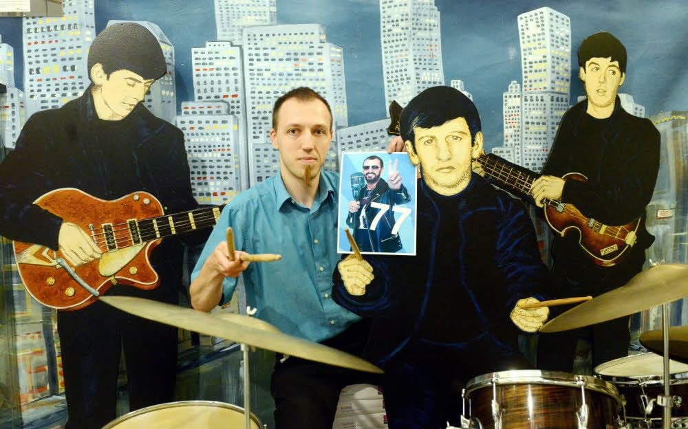 Beatles-Museumsgeschäftsführer Stefan Lorenz neben Papp-Figur Ringo Starr, in der Hand das Geburtstagsplakat für den Drummer.
