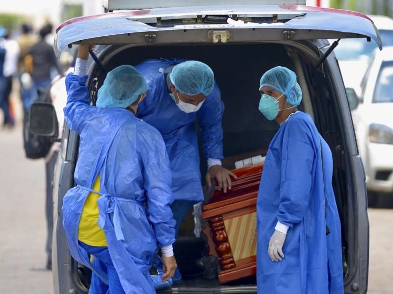 Männer mit Schutzanzügen laden in der Hafenstadt Guayaquil in Ecuador einen Sarg in einen Wagen vor einem Krankenhaus. Foto: Marcos Pin Mendez/dpa