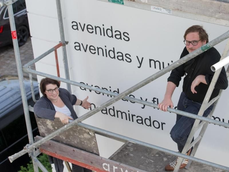 Die Hausbesitzer Helen und Marcus Knauf stehen auf einem Gerüst an der Fassade ihres Hauses in Bielefeld. Das angeblich sexistische Gedicht „Avenidas” von Eugen Gomringer schmückt die Außenwand der Jugendstil-Villa. Foto: Friso Gentsch