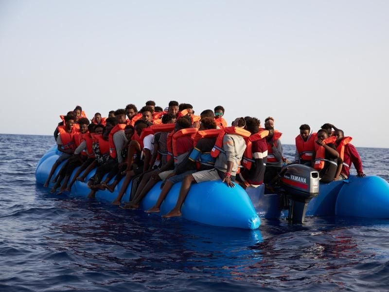 Flüchtlinge sitzen vor der Küste von Libyen in einem Schlauchboot, bevor sie vom Hilfsschiff „Alan Kurdi” gerettet werden. Foto: Fabian Heinz/Sea-Eye
