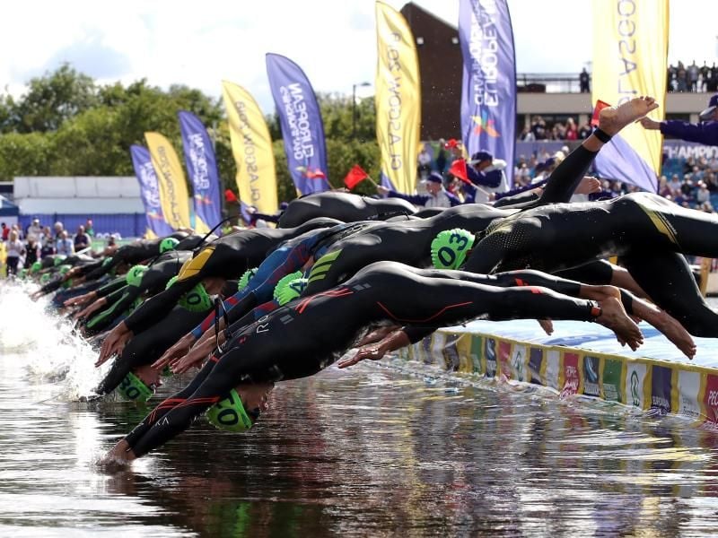 Die Teilnehmer des Männer-Triathlons springen beim Start in Glasgow ins Wasser. Foto: John Walton
