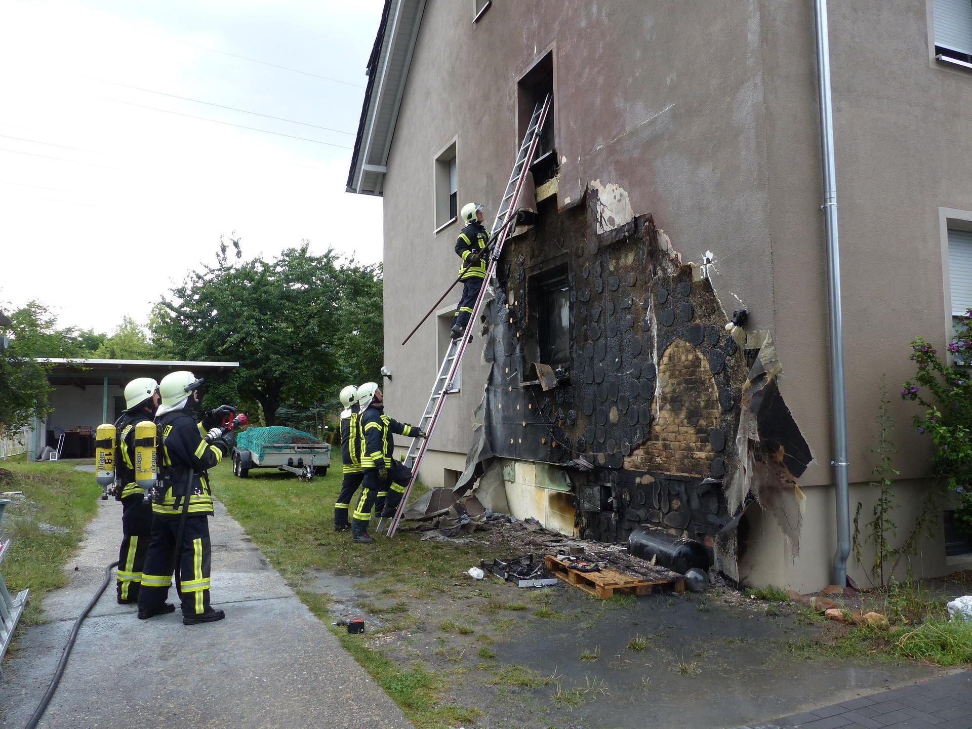 Einsatzkräfte der Feuerwehr gehen Löscharbeiten nach einer Explosion an einem Haus nach.