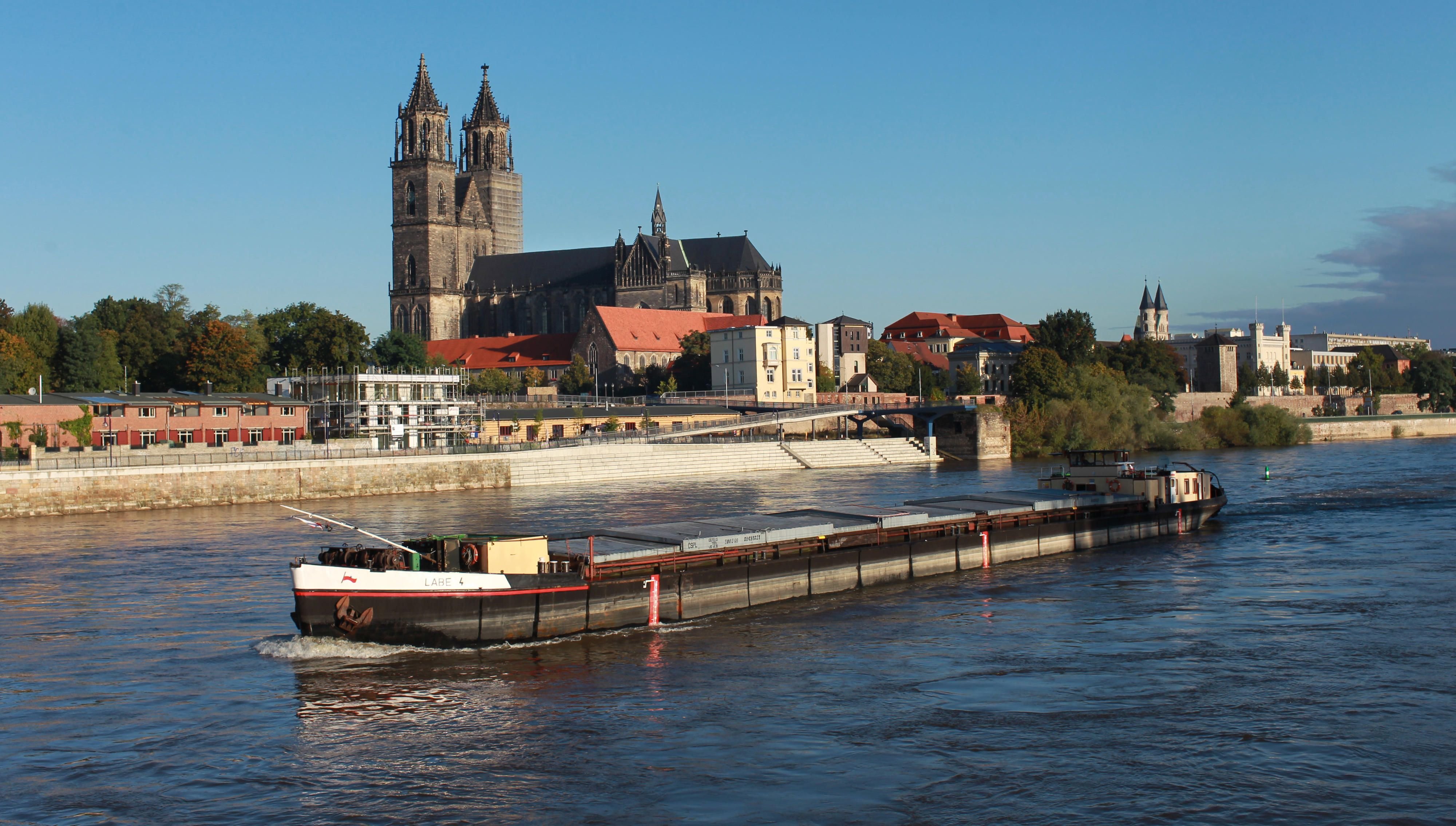 ein Schiff aus der Tschechischen Republik passiert in Magdeburg den Engpass am Domfelsen unterhalb des Domes "Sankt Katharina und Sankt Mauritius".