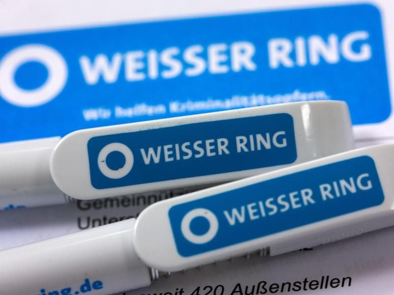 Kugelschreiber mit dem Logo des Weißen Rings liegen auf einem Tisch. Foto: Jens Büttner/Archiv
