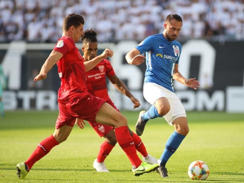 Rostocks Pascal Breier (r) wird von Daniel Didavi (M) und Mario Gomez unter Druck gesetzt. Foto: Danny Gohlke