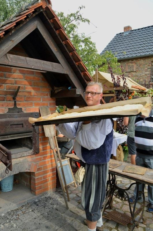 Hobbybäcker Jan Berger schiebt die rohe Kartoffel-Teigmasse in den Holzofen.