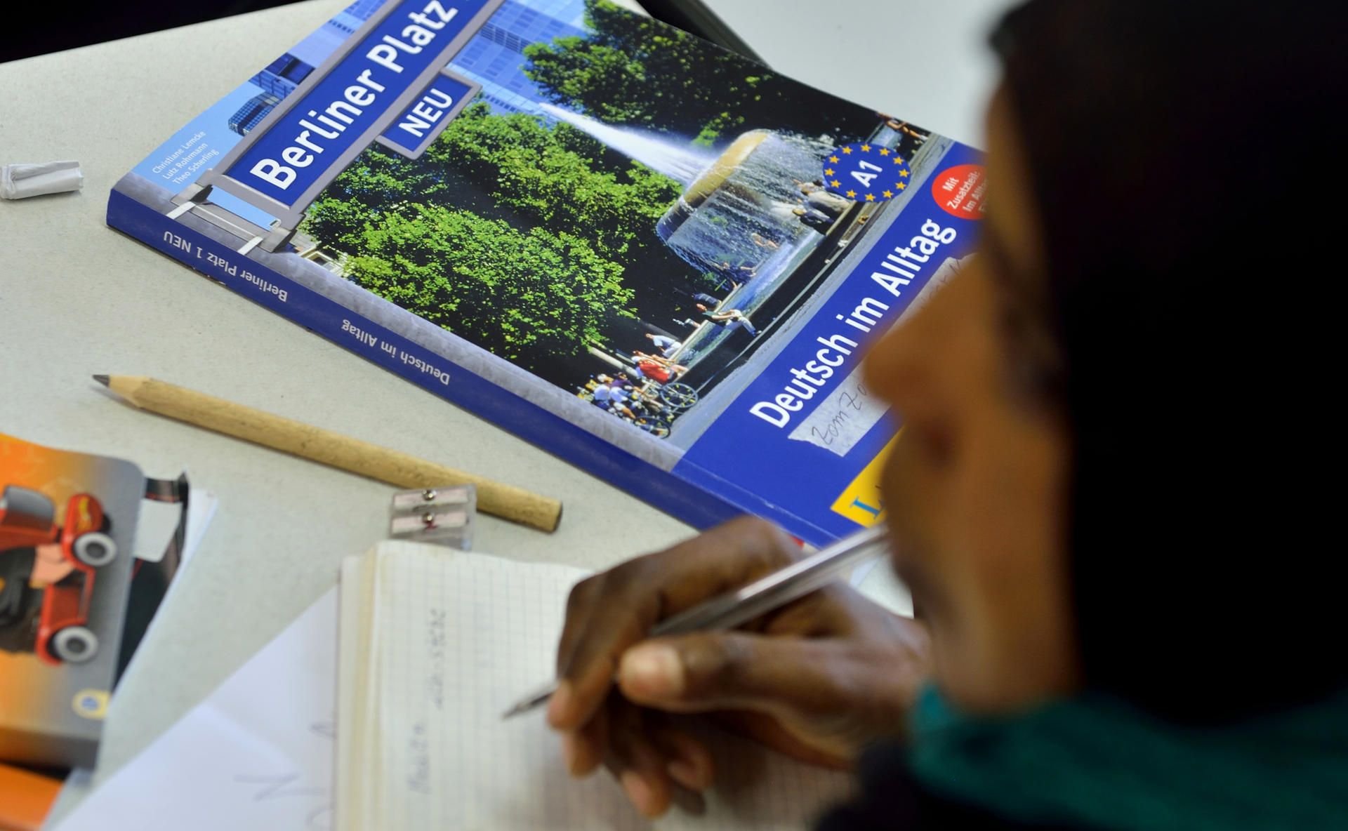 Das Lehrbuch «Deutsch im Alltag» liegt in einem Deutschkurs für Flüchtlinge vor einer jungen Frau auf der Schulbank.