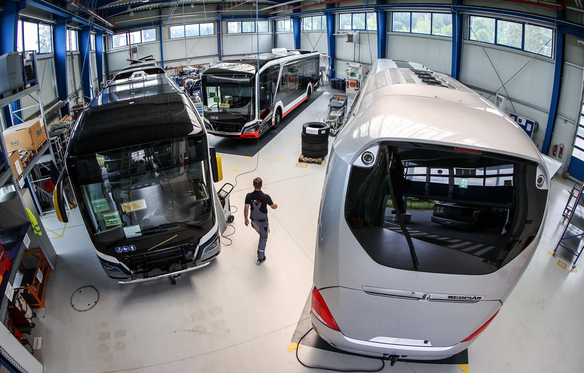 Plauen: Ein Mitarbeiter des MAN Bus Modification Centers (BMC) geht durch eine Halle mit Elektrobussen MAN Lion's City E (links).