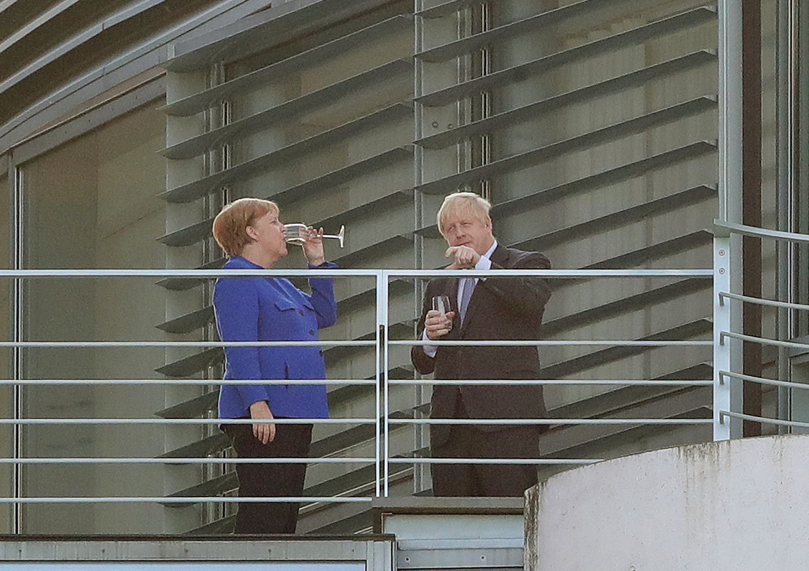 Bundeskanzlerin Angela Merkel (CDU) trinkt mit Boris Johnson, Premierminister von Großbritannien, bei ihrem Treffen im Bundeskanzleramt auf einem Balkon ein Getränk.