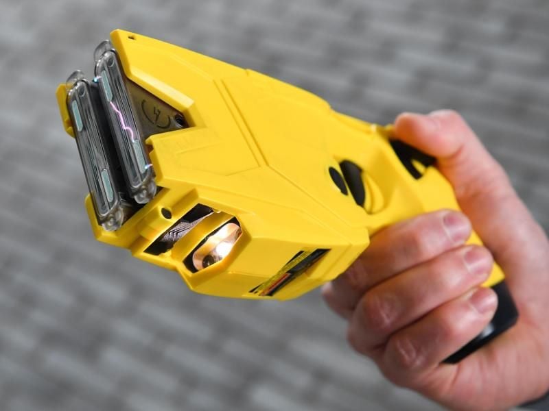 Eine Hand hält einen mit zwei Simulationskassetten bestückten „Distanz-Elektroimpulsgerät” (DEIG) Taser X2. Foto: Arne Dedert/Archiv