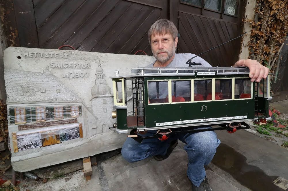 Karl Kesselring zeigt einen nachgebauten Triebwagen der Kleinbahn und das von ihm hergestellte Betonrelief mit dem Motiv Hettstedter Saigertor.
