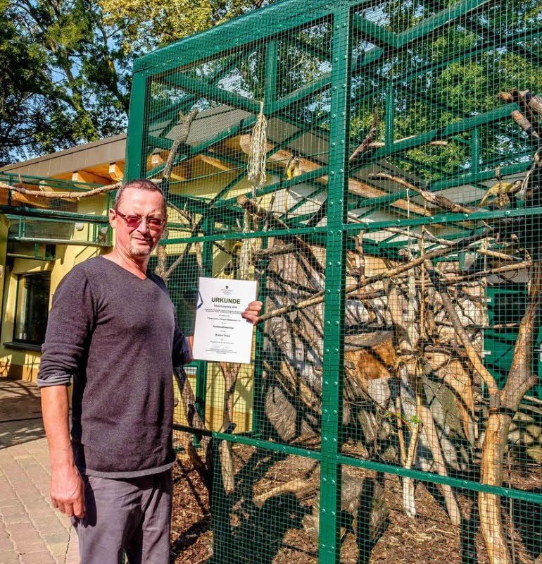 Mario Lindemann, Leiter des Tierparks, präsentiert vor der Krallenaffenanlage die Urkunde des Umweltministeriums.
