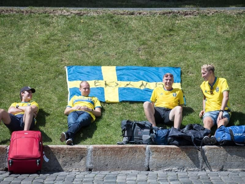 Schwedische Fußballfans ruhen sich in der Nähe des Roten Platzes auf einer Wiese aus. Foto: Federico Gambarini
