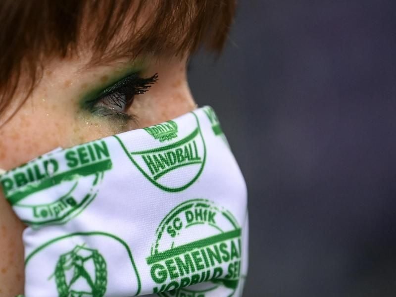 Eine junge Frau trägt eine Maske mit dem Logo des Vereins. Foto: Hendrik Schmidt/dpa-Zentralbild/dpa