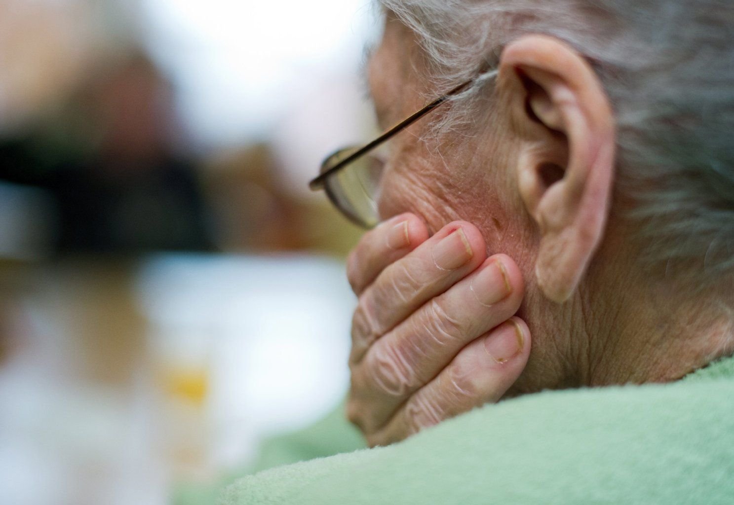 Eine alte Frau sitzt in einem Pflegeheim.
