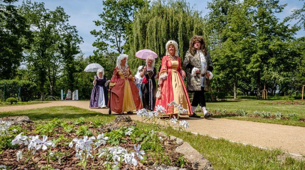 Kurfürst August der Starke und seine Gemahlin Christiane Eberhardine lustwandeln durch ihren Park. Offenkundig sind sie ganz zufrieden mit den Taten der fernen Nachkommen.