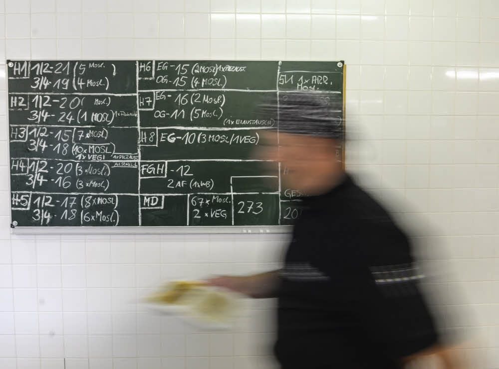 Auf einer Tafel wird vermerkt, wie viele Portionen für welches Hafthaus und welche Wohngruppen vorbereitet werden müssen. Eine Kostprobe muss täglich für die Behörden eingefroren werden.