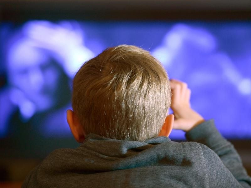 Ein Junge sitzt vor dem Fernseher. Foto: picture alliance / dpa