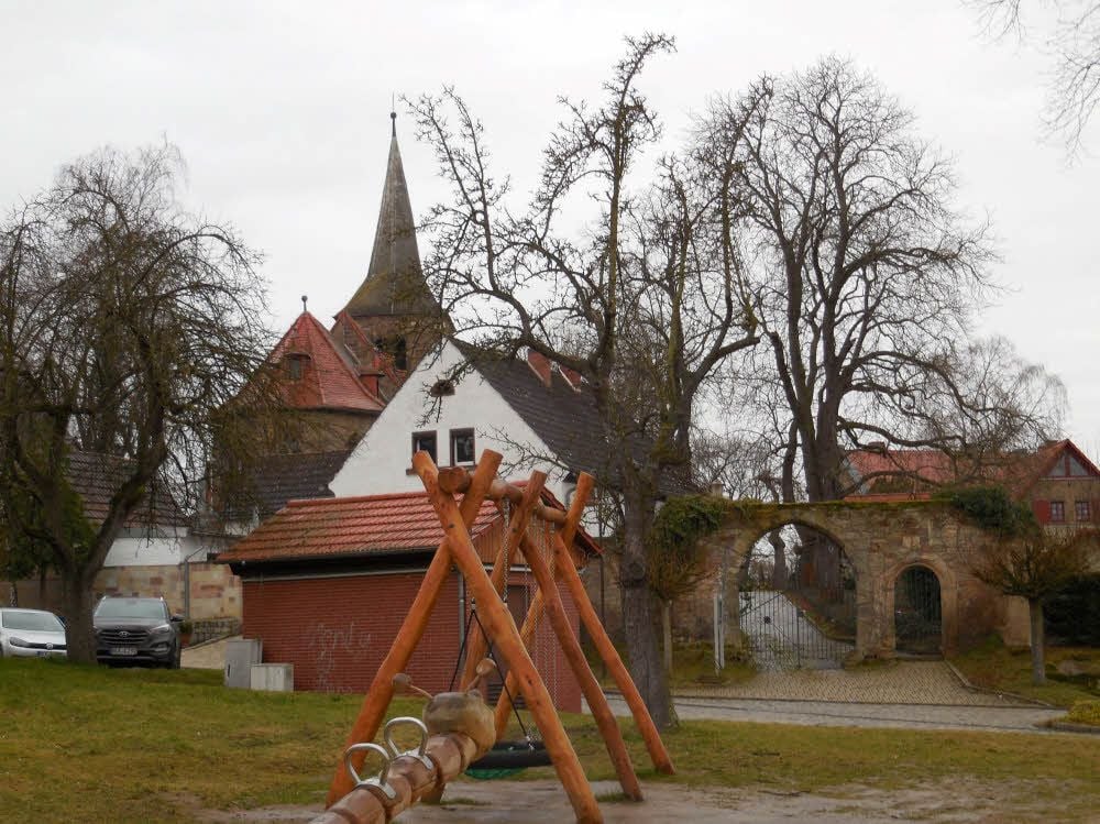 Im Vordergrund ein Teil des im Oktober 2017 eingeweihten Spielplatzes von Kirchscheidungen. Dahinter die Dorfkirche St. Johannes.