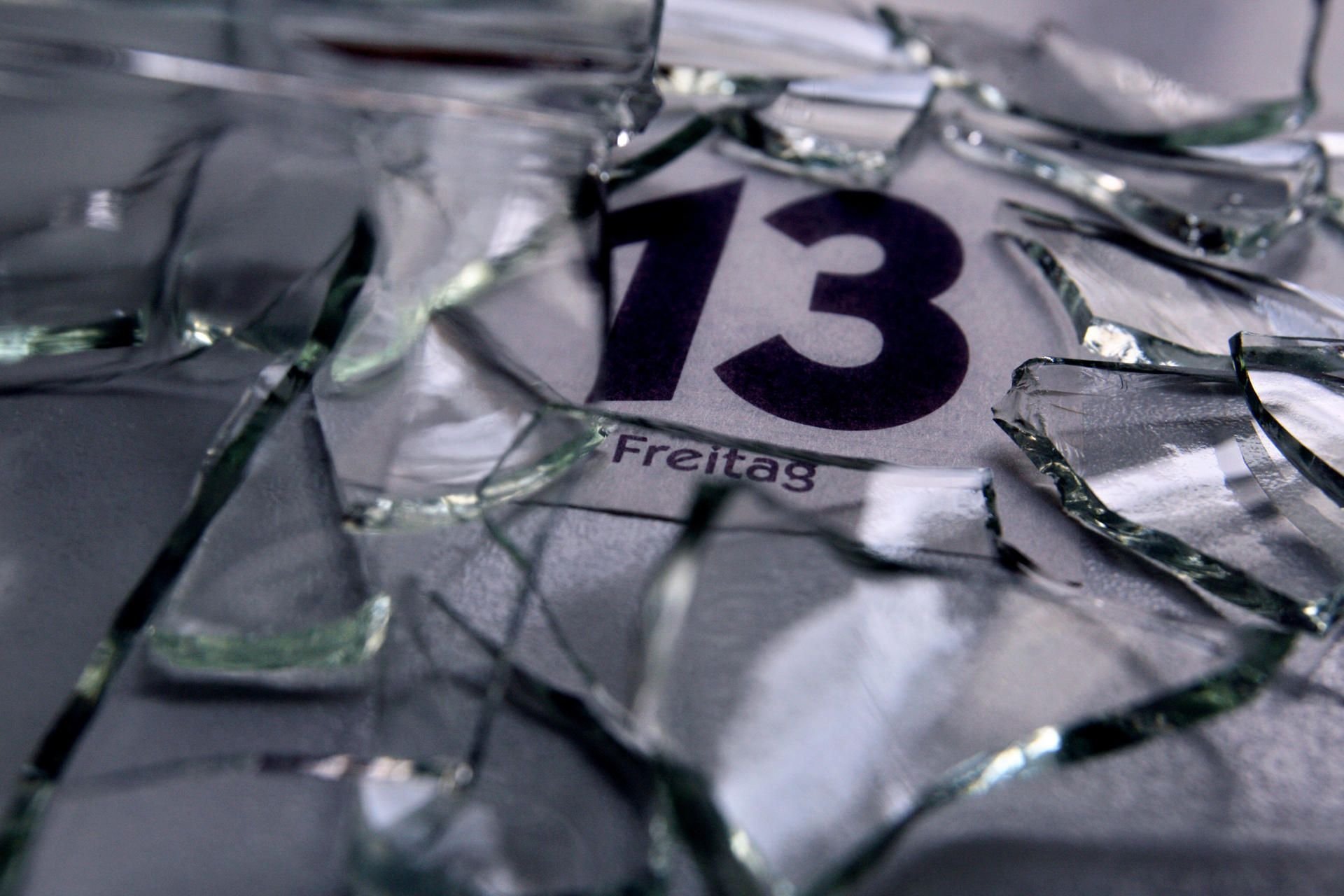 Ein Kalenderblatt mit dem Datum von Freitag dem 13. liegt unter Glasscherben.