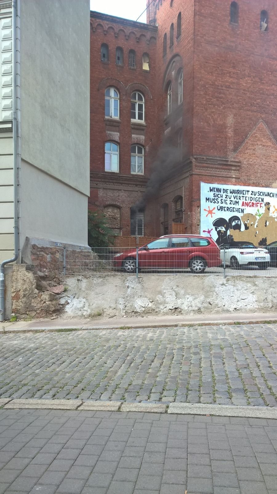 Eine Rauchsäule steigt aus dem Fenster auf.