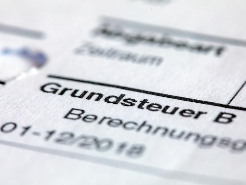 ILLUSTRATION - Ein Abgabenbescheid für die Entrichtung der Grundsteuer liegt auf einem Schreibtisch. Foto: Jens Büttner/Archivbild