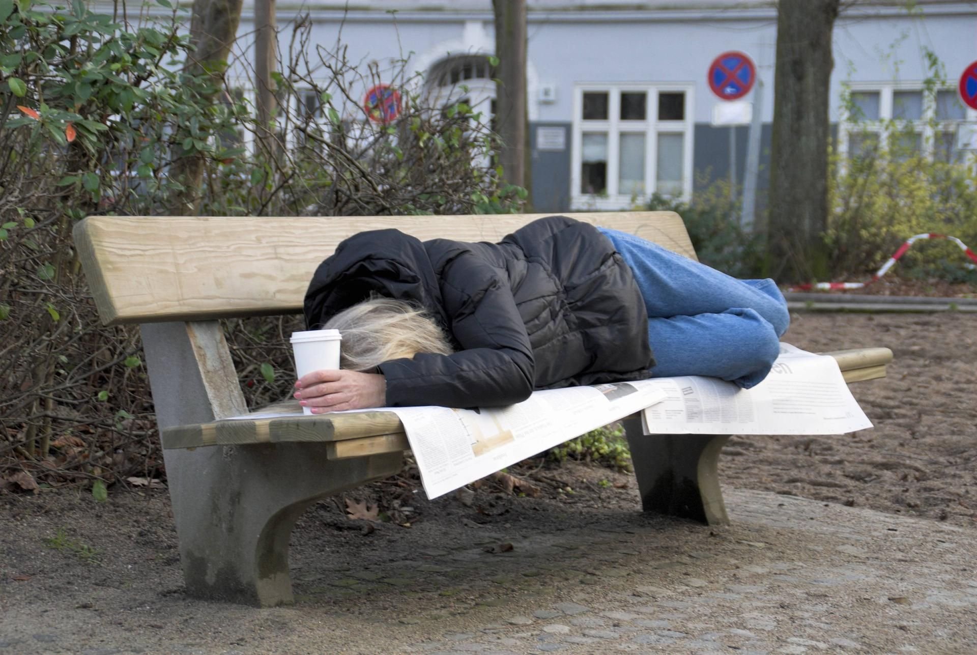 Ein Obdachloser auf einer Parkbank.