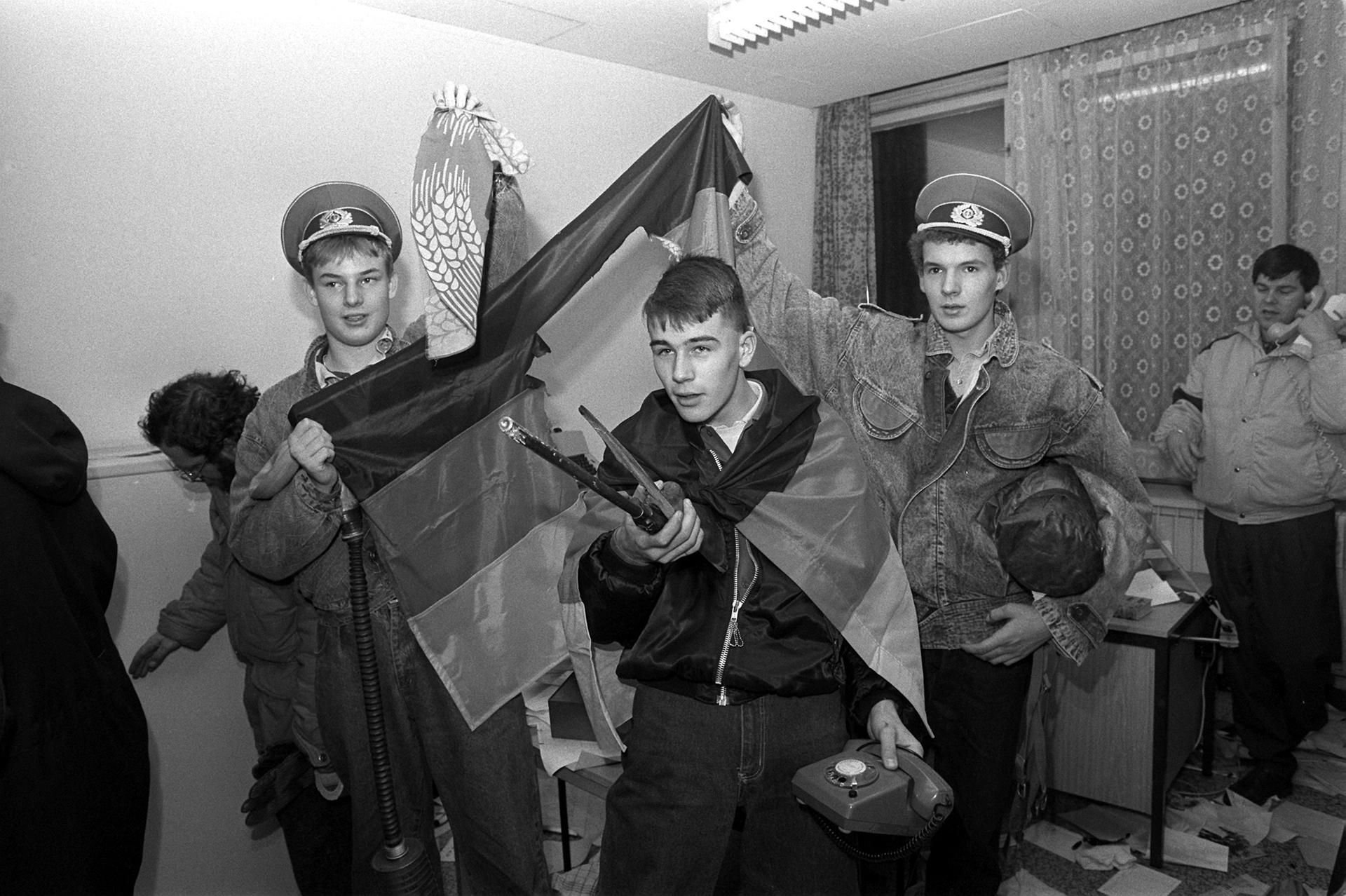 Eine Gruppe Demonstranten mit der DDR-Flagge in einem verwüsteten Büro der Zentrale des Amtes für Nationale Sicherheit in Ost-Berlin am 15.01.1990.