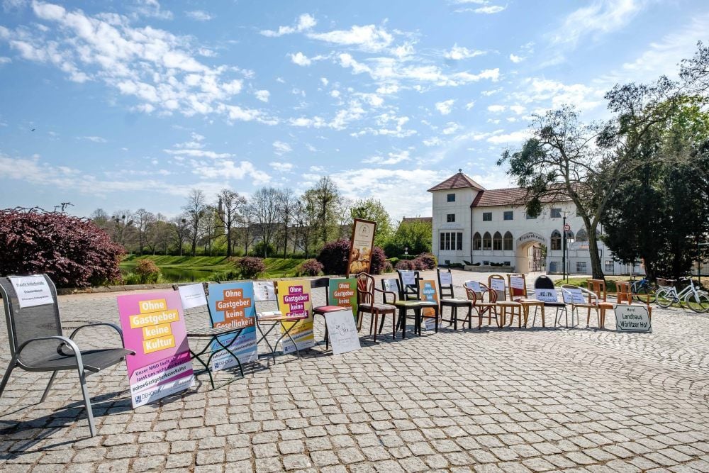 Vorm Eichenkranz in Wörlitz haben Gastronomen Stühle und Plakate aufgestellt. Die leeren Stühle stehen für ausbleibende Gäste.