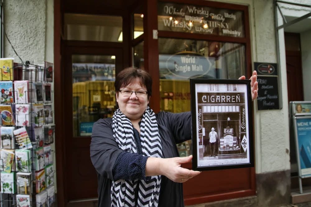 Margrit Kolodziej mit einem Foto des früheren Ladenbesitzers Arthur Rumstedt vor ihrem Geschäft in der Sangerhäuser Bahnhofstraße