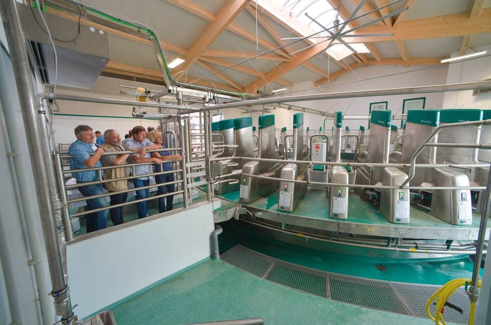Quirin Forster (vorn, 2. v. l.) zeigt das neue Melk-Karussell. Dort sollen Kühe aus dem benachbarten Stall gemolken werden.