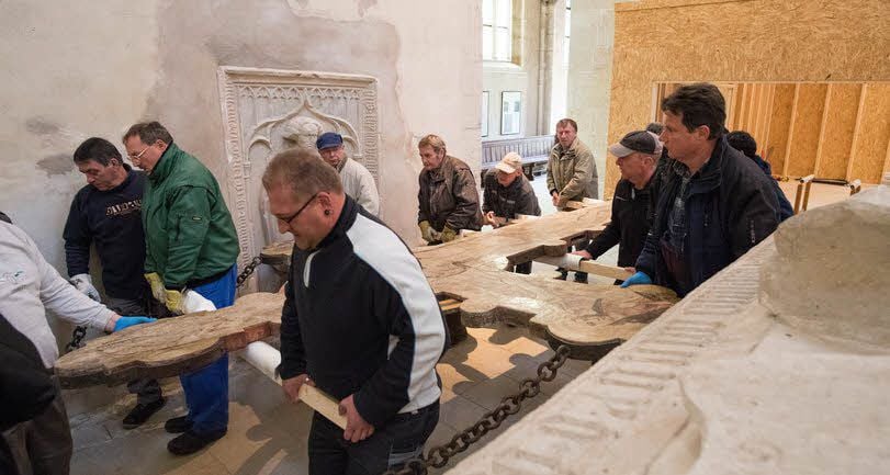 Helfer tragen das Triumphkreuz aus der in der Kirche provisorisch errichteten Werkstatt.