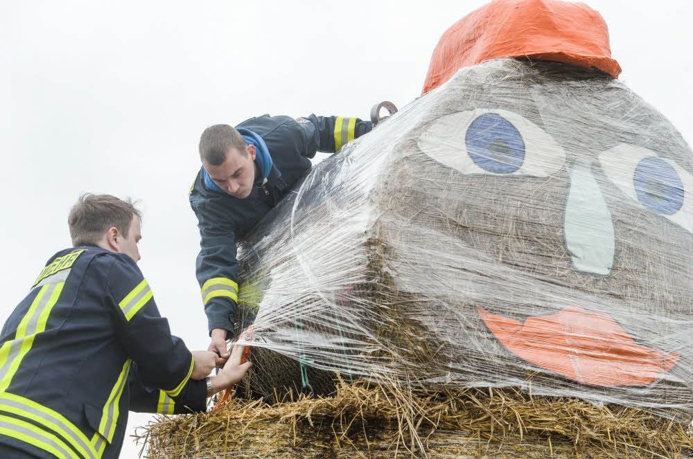Benjamin Kiel und Christian Klaus (r.) umhüllen den Strohkopf mit Folie, damit er geschützt vor Wind und Wetter ist.