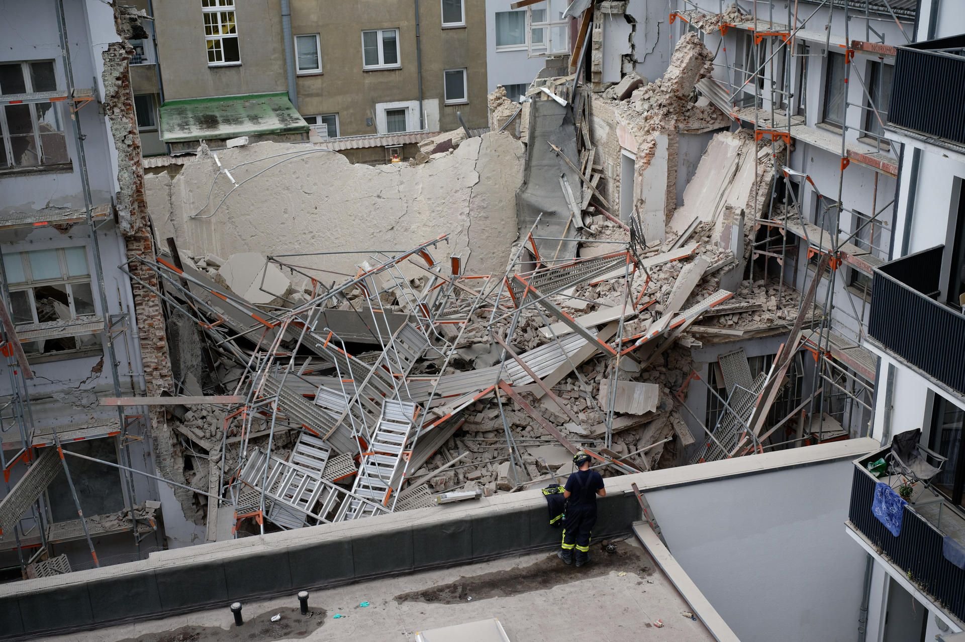 Düsseldorf: Einsatzkräfte der Feuerwehr stehen vor dem eingestürzten Gebäude und Gerüst