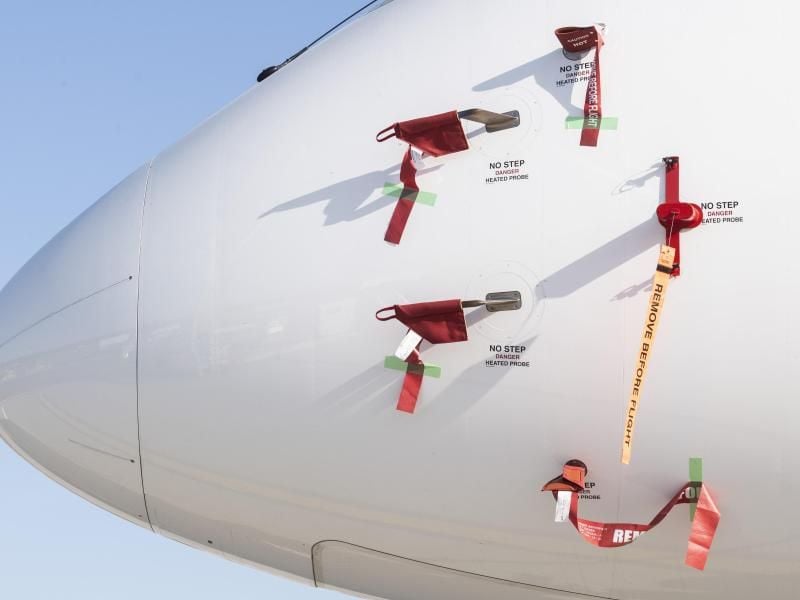 Bänder mit der Aufschrift „Remove Before Flight” (dt. Vor dem Flug entfernen) sind an einem Flugzeug der Schweizer Fluggesellschaft Swiss befestigt. Foto: Ennio Leanza/KEYSTONE/dpa