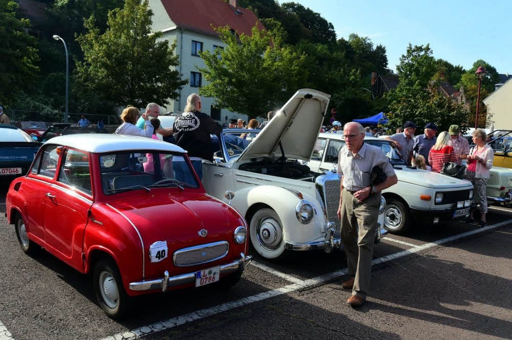 Die Vielfalt der Fahrzeuge beeindruckt und zieht die Menschen an. Es sind auch viele Cabriolets zu sehen, in denen die Teilnehmer die Ausfahrt genießen.
