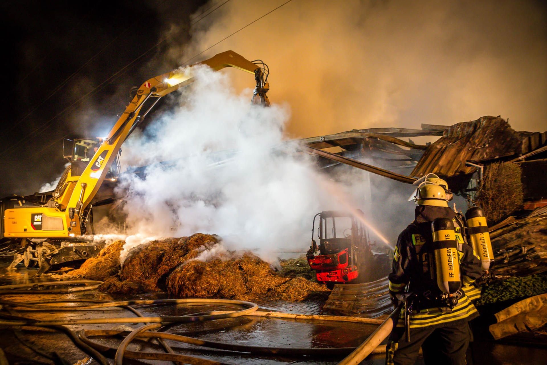 Ein Feuerwehrmann löscht ein Feuer auf einem Reiterhof in Hofheim. Bei dem Brand waren rund 1500 Heuballen in Flammen aufgegangen und mussten vor dem Löschen mit Baggern auseinandergezogen werden.