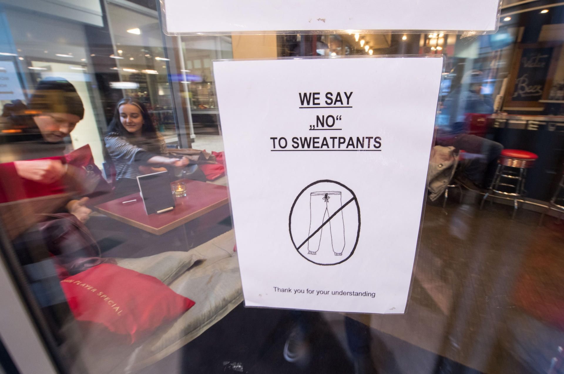 Ein Schild mit der Aufschrift „We say 'no' to sweatpants - Thank you for your understanding“ hängt in Stuttgart an der Eingangstür eines Cafés.