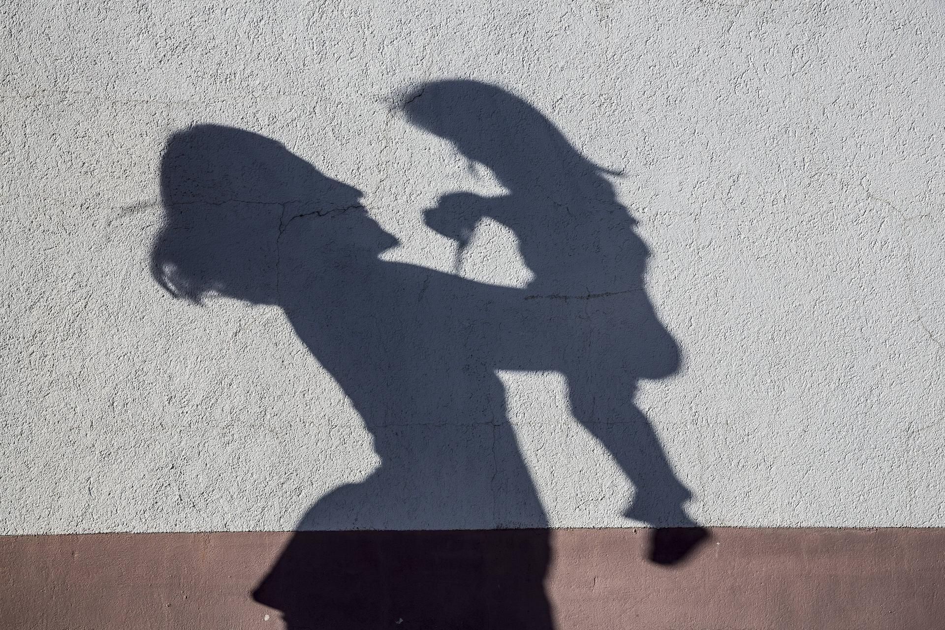 Eine Frau und ein Kind werfen Schatten auf eine Wand.