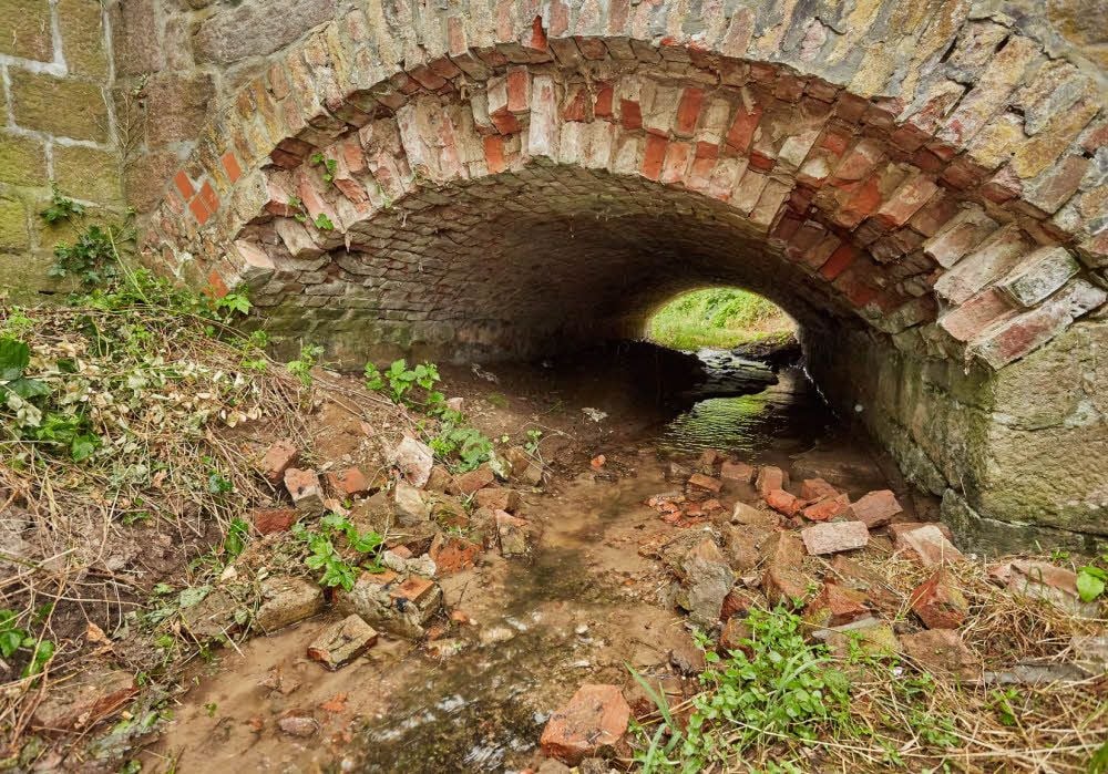 Aus dem Bogen der Brücke liegen Steine im schmalen Bachbett. Die Tragfähigkeit ist laut eines Gutachtens nicht mehr gewährleistet.