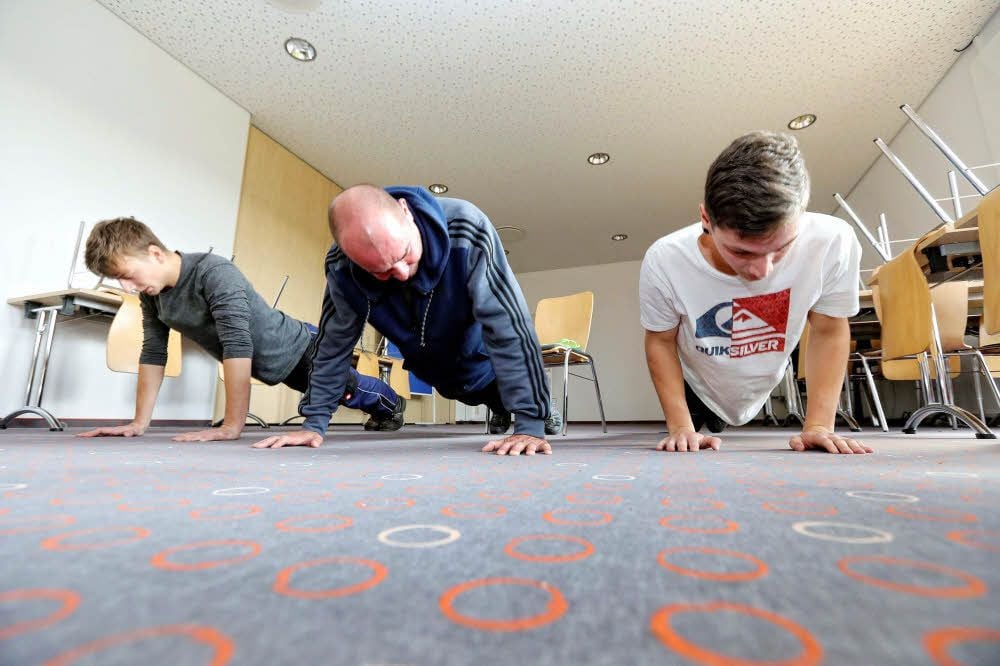 Gesundheitstag im Bildungszentrum für Beruf und Wirtschaft in Wittenberg: Uwe Fabian, Trainer beim SV Grün-Weiß Wittenberg-Piesteritz (Mitte), demonstriert mit Erik Meiwald (links) und Julius Häcker korrekte Liegestütze.